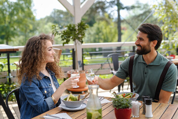 Young couple at date in restaurant, sitting on restaurant terrace. Boyfriend and girlfriend...