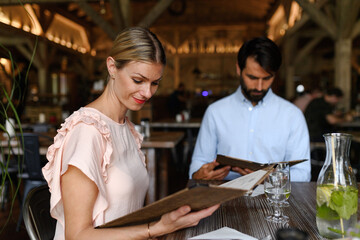 Husband and wife choosing food from menu. Happy loving couple at date in restaurant. - 755175850