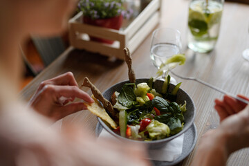 Close up of vegetable salad serving in restaurant, customer eating healthy food from bowl.