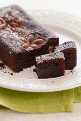 Closeup of juicy chocolate brownie of a pie decorated with sugar powder and almond on a glass plate. - 755176802