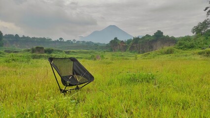 An empty black portable seat in savana of natural park near by mountainous area