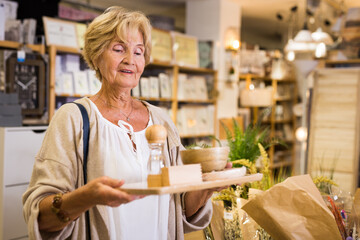Senior woman customer holding purchases and walking in a household goods store