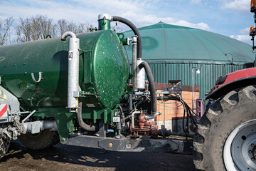 Modernes Güllefass mit angebauter Scheibenegge beim Absauen von Gärresten aus einer Biogasanlage,...