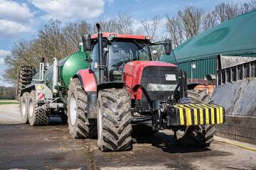 Modernes Güllefass mit angebauter Scheibenegge beim Absauen von Gärresten aus einer Biogasanlage,...