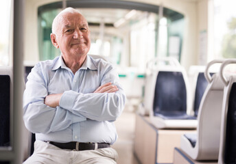 Elderly Caucasian man sitting in tram and looking in camera.