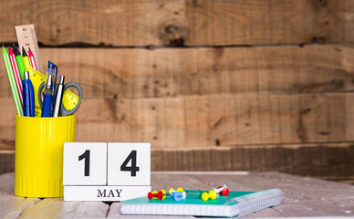 May calendar background with number  14. Stationery pens and pencils in a case on a wooden vintage...