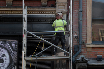 The builder stands on the scaffolding