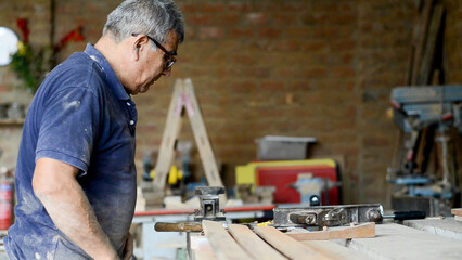 A mature carpenter standing confidently in his workshop. RAW video record.