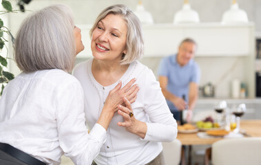 Fototapeta premium As two elderly woman meet, they exchange warm greeting by embracing with a gentle kiss on the cheek