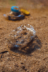 Abandoned plastic trash on the beach, in the foreground broken bottle