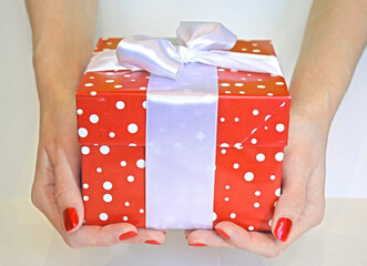a large box with a bow with a holiday gift in female hands on a white background. congratulations...