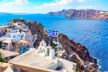 Poster Greek orthodox church with bells, greek flag and famous white houses on Santorini island, Aegean sea, Greece. © Nikolay N. Antonov