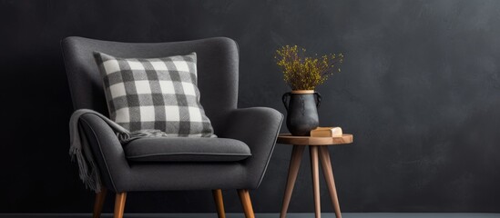 A stylish armchair with a pillow and plaid placed near a dark wall, accompanied by a small wooden table holding a vase with a plant in a pot.