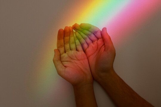 a person's hands are painted with rainbow colors. Photo with the theme of sexual orientation and fluidity.