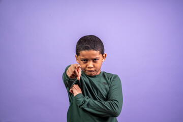 Hispanic Boy looks at the camera with a grimace pointing at the camera