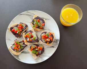 Plato con molletes y jugo de naranja. Molletes: comida típica de México hecha con pan, frijoles, queso, jitomate, chiles verdes, cebolla y cilantro. 