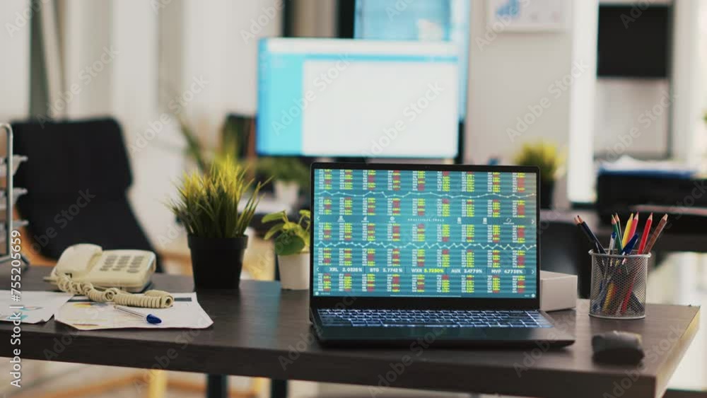 Poster desk in empty office with laptop showing stock exchange data collected to develop trading strategies