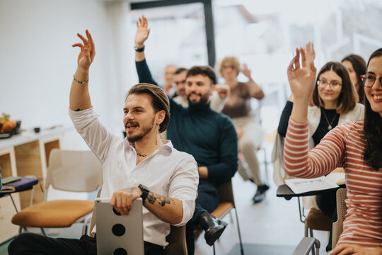 An engaged audience participating in a QA session at a workshop. People with raised hands are eager to interact, contribute or ask questions.