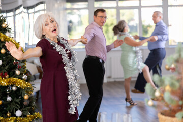 Middle-aged man and elderly woman are dancing contemporary discofox in couple during lesson at studio in New Year atmosphere. Leisure activities and hobby for positive people.