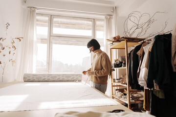 Focused 35-year-old woman in her sunny, well-organized workshop.