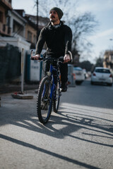 Focused man cycling in urban environment wearing casual winter clothing and headphones, portraying active city lifestyle.
