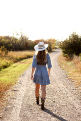 Girl with Cowboy Hat Walking Down Dirt Road