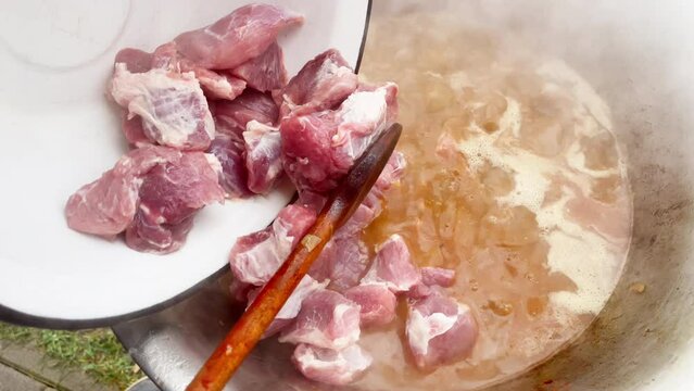 Chopped pork pieces goes to kazan with boiling Goulash while Preparation traditional "Goulash" soup or meat stew and vegetables cultural meal masterpiece in Czech Republic and Slovakia countries.