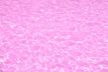 Transparent pink clear water surface texture with ripples, splashes and bubbles. Close Up pink water wave texture with reflection sunlight. Beautiful water ripple wave with copy space