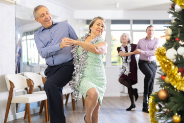 Happy caucasian adult man and lady dancing rock and roll dance in modern dance studio during celebration Christmas and New Year