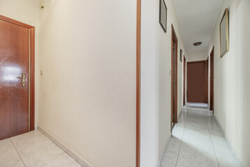 Distributor hallways of a house with light stoneware floors, different sapelly wood doors and armored street door