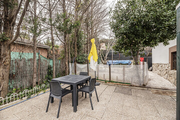 A synthetic material table with gaming chairs on a plot with terrazzo floors and fruit trees