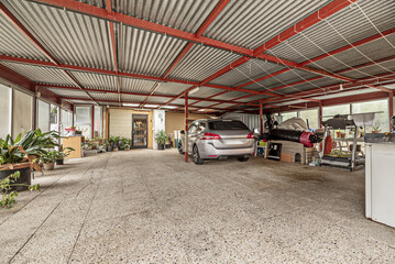 a porch with sliding translucent glass doors, a corrugated metal roof and a vehicle parked...