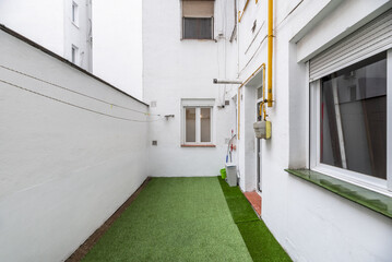 Interior patio of a house with white painted walls, natural gas meter with yellow pipes and artificial grass floors in a ground floor home