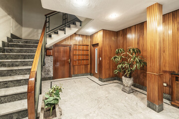 Access portal to a residential building with light marble floors, wood-paneled walls and elevator...