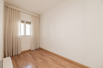 An empty room with light wooden floors and a double aluminum window with long white curtains
