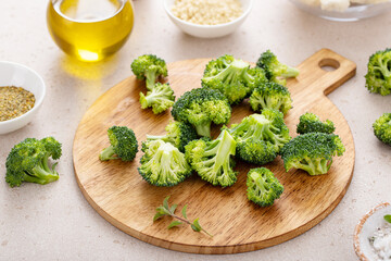 Raw broccoli florets on a cutting board, ready to roast with spices and olive oil - 755236219