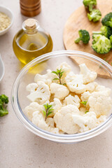 Raw cauliflower florets in a glass bowl, ready to roast with spices and olive oil