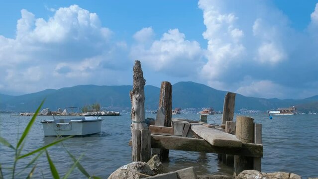 Forsaken boat by pier. A view of forsaken old boat moored by the pier in the calm lake water in summer.