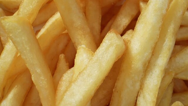 French fries, a beloved staple of fast food culture, are made from potatoes cut into thin strips and deep-fried until crispy. They are typically seasoned with salt and served hot. Food concept. 4K.
