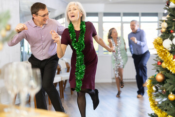 Happy senior woman and man enjoying active boogie-woogie dance in modern studio during celebration...