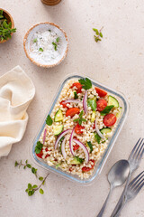 Pearl couscous salad with fresh vegetables and herbs in a meal prep container, healthy lunch or side dish - 755238665