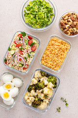 Healthy vegetarian meal prep with boiled eggs, roasted vegetables, cooked lentils, couscous salad and nuts