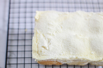 Close up of Milk Bun Thailand is a soft bread with a topping of powdered sugar, milk and vla filling,soft focus texture, served on black tray. white background. makanan viral indonesia