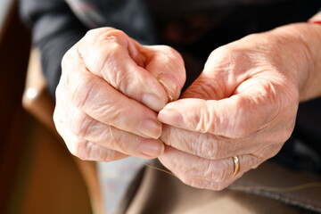 針に糸を通す高齢女性の指先