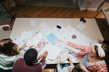 Top view of a multigenerational team engaging in a collaborative effort during a dynamic and creative business meeting with documents and ideas on display.