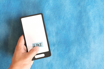 Hand holding a mobile phone paper cutout hitting word like. Social media concept.