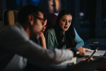 Professional team in deep discussion during a late-night office meeting, showcasing teamwork and collaboration.