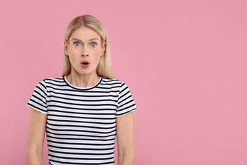 Portrait of surprised woman on pink background, space for text