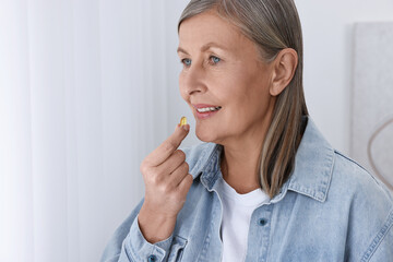 Beautiful woman taking vitamin pill at home