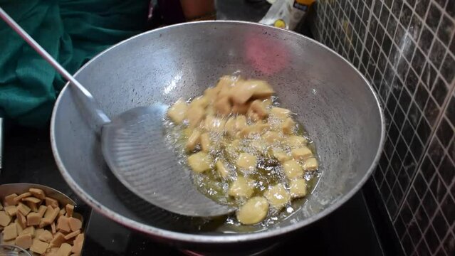 Video of snacks frying in hot oil during Diwali festival. Home cooked, healthy, unhealthy, tasty, sweet, shakkar para, shankar pali, pan, women, crunch, process, puri, wheat flour, kitchen, Indian.